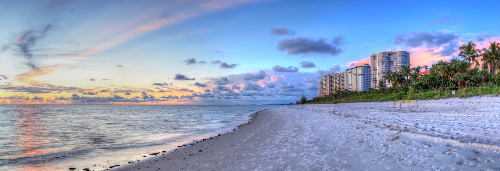 View of the beach at sunset with tall buildings in the background