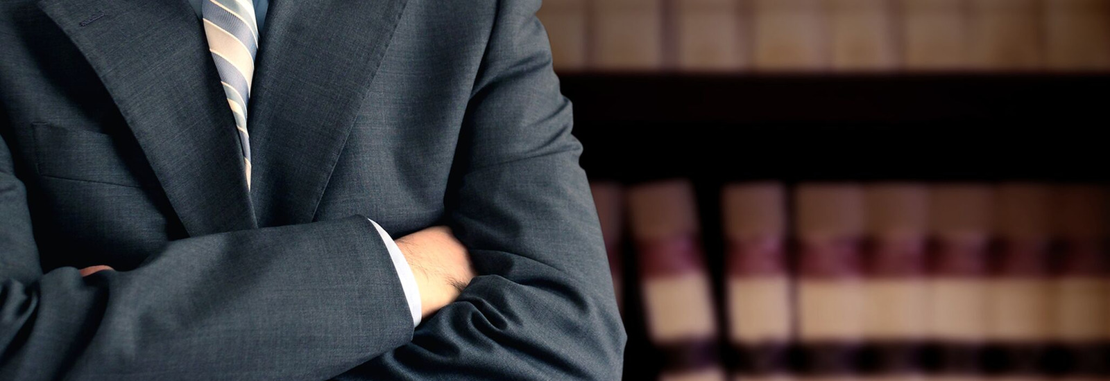 Lawyer with his arms folded in front of book case