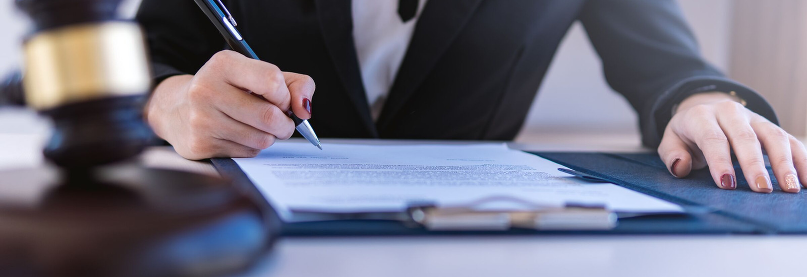 Woman writing on a document with a gavel blurred in the foreground 